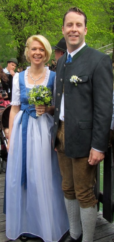 A couple in traditional Bavarian dress: a woman in a blue dirndl and a man in a Tracht jacket and lederhosen